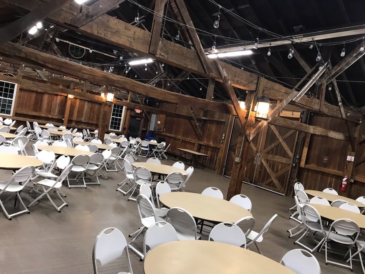 A large room filled with tables and chairs in a barn.