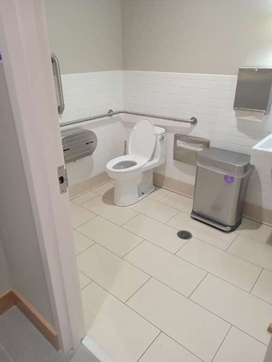 A bathroom with a toilet, sink, and a trash can.