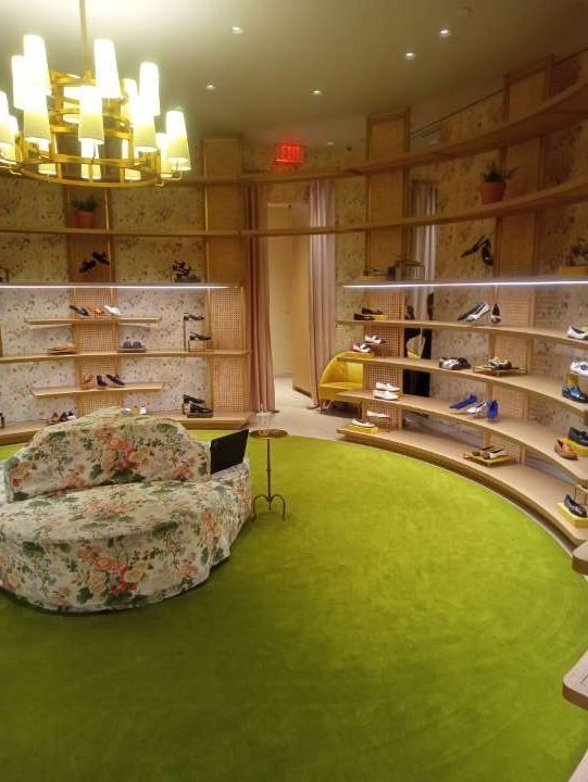 A room with a couch and shelves filled with shoes.
