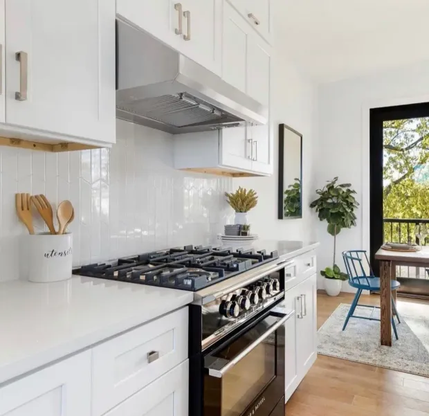 White kitchen with stainless steel range, white cabinets, and a view of a deck.