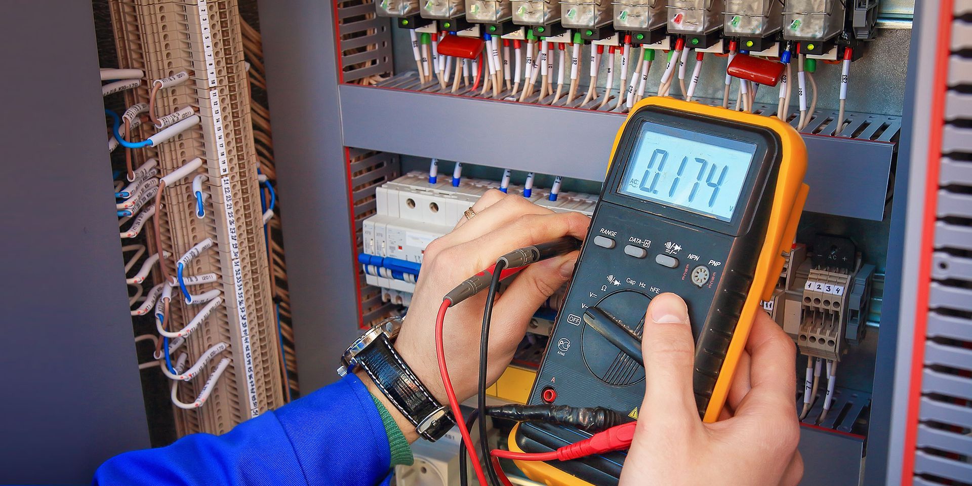 An electrician holding a digital multimeter in their hands.