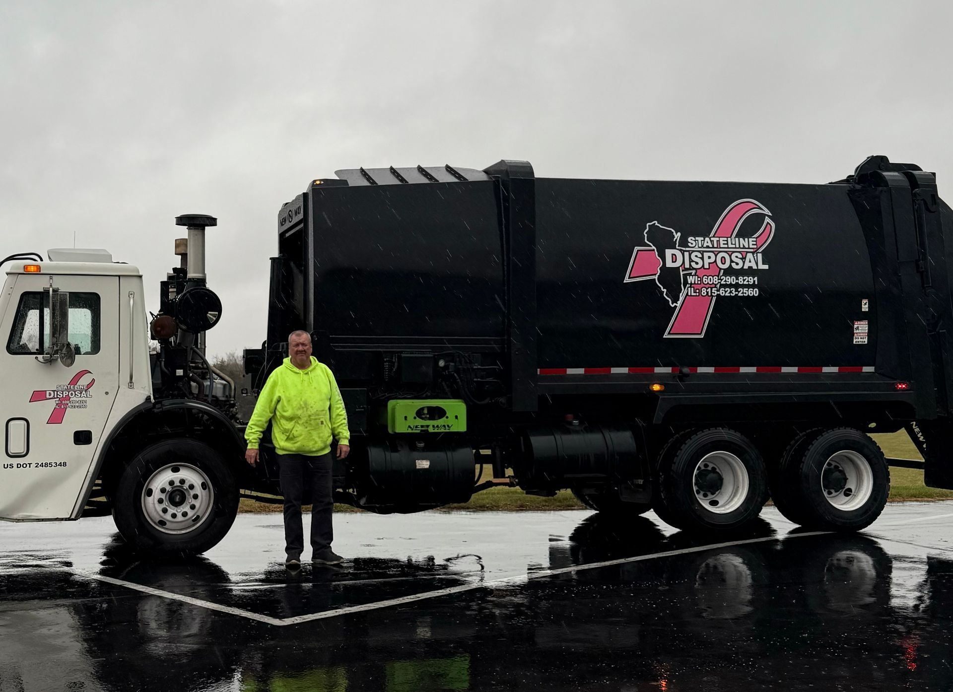 A man is standing in front of a garbage truck