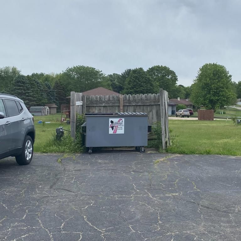 a car is parked next to a dumpster in a driveway