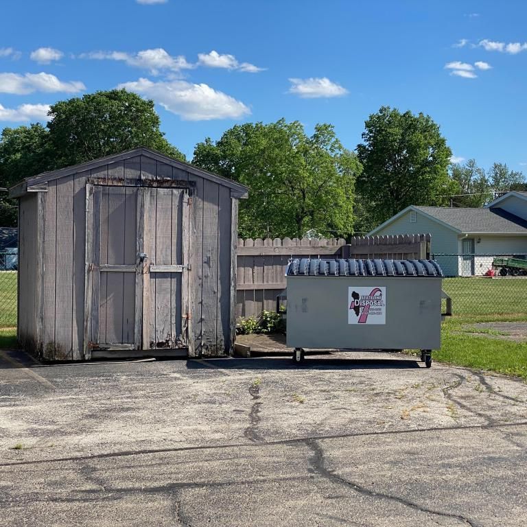 a wooden shed and a dumpster in a driveway