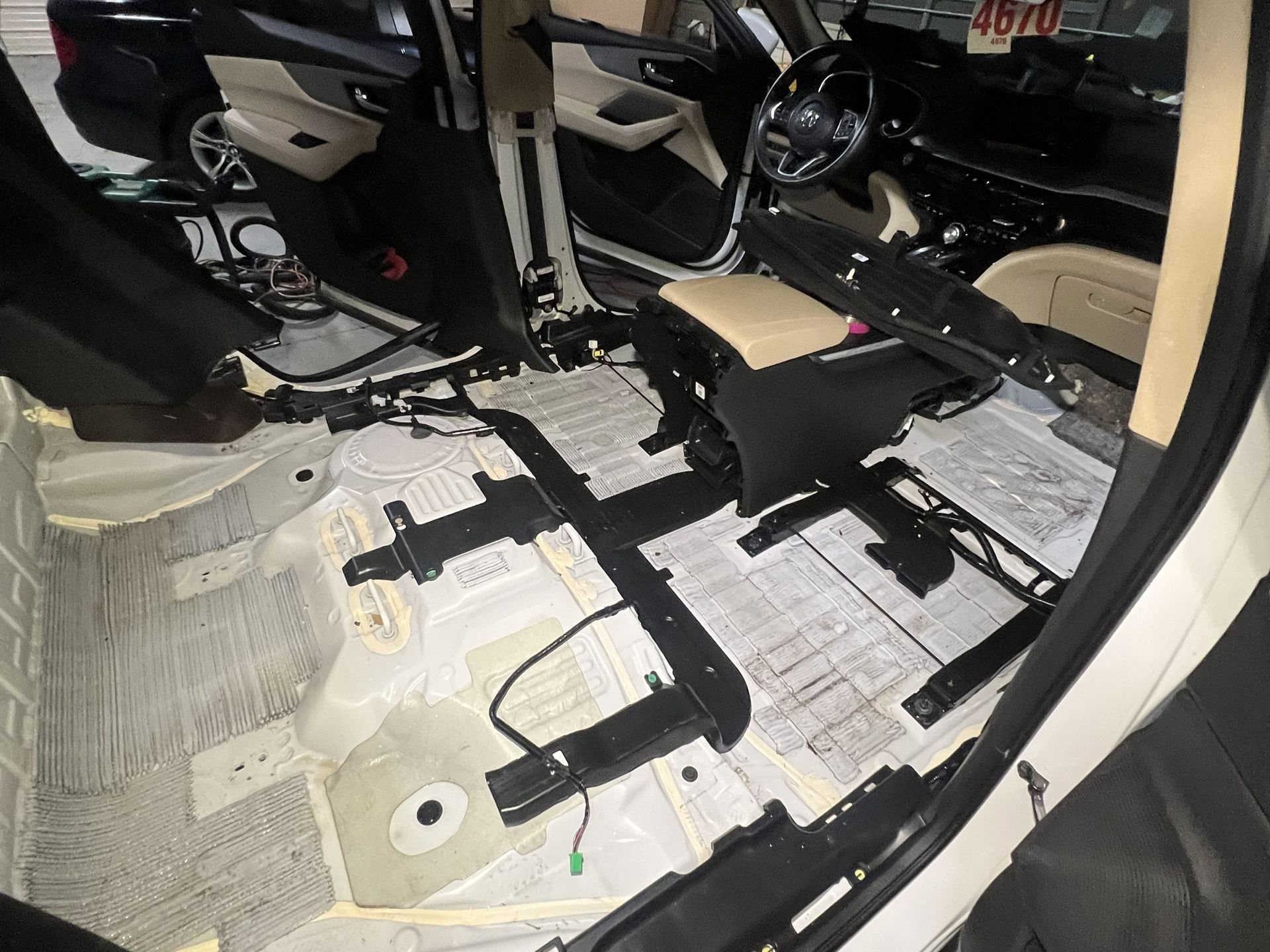 Car interior with seats removed, exposing the bare floor and seat mounting brackets.
