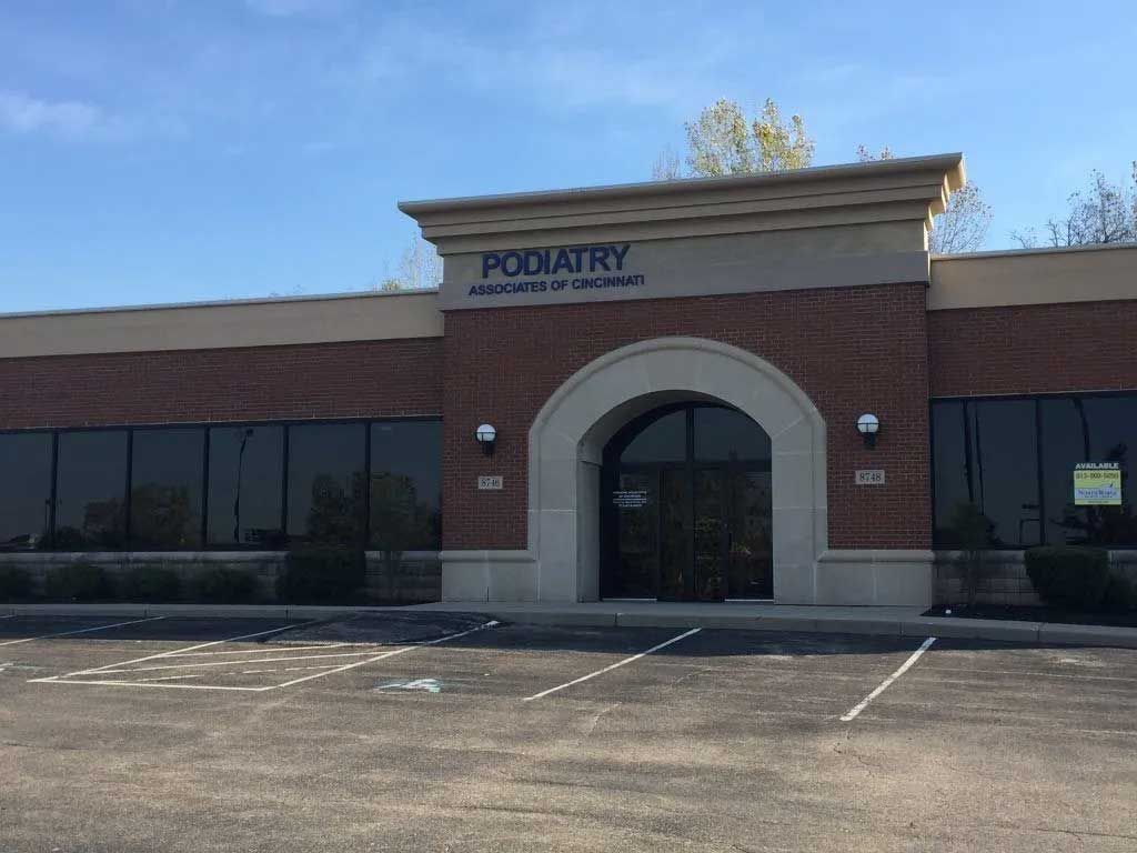Exterior of a podiatry office with a brick facade and arched entrance under a sign that reads, 