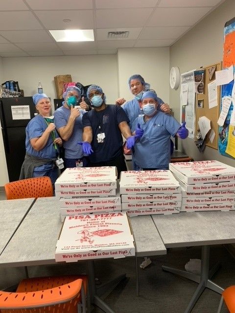 A group of people standing around a table with pizza boxes on it