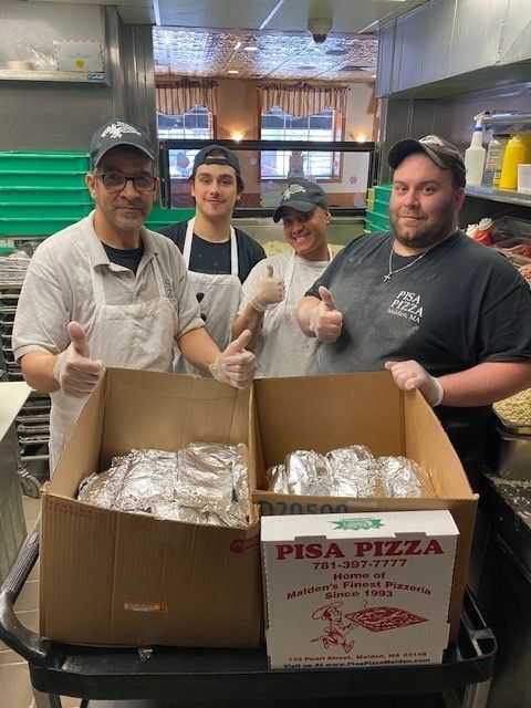 A group of men standing next to a box that says pisa pizza