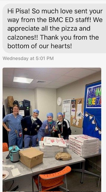 A group of people standing around a table with pizza and calzones on it