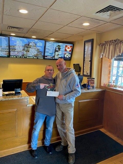 Two men are standing next to each other in a restaurant holding a check.