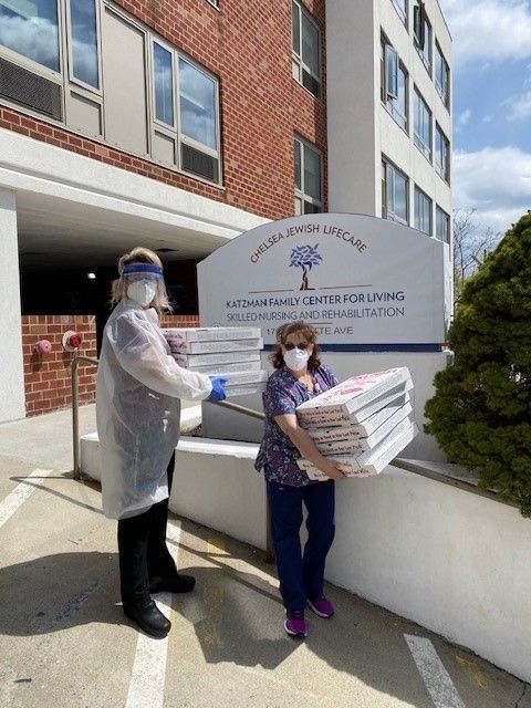A man and a woman carrying boxes in front of a building