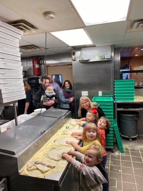 A group of children are making pizza in a kitchen