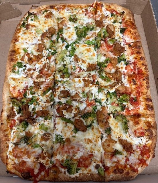 A pizza with broccoli and sausage is in a box