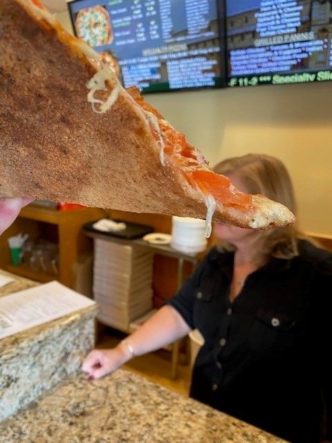 A woman is holding a slice of pizza over her head