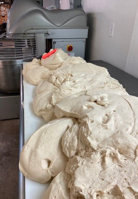 A pile of dough is sitting on a table in front of a mixer.