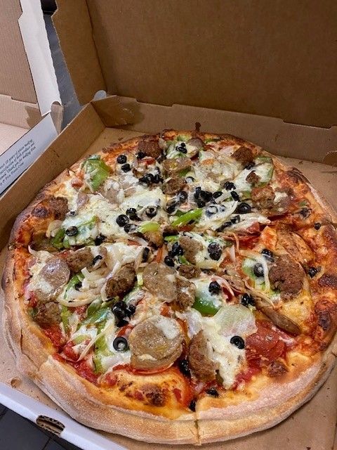 A pizza with a lot of toppings is in a cardboard box.
