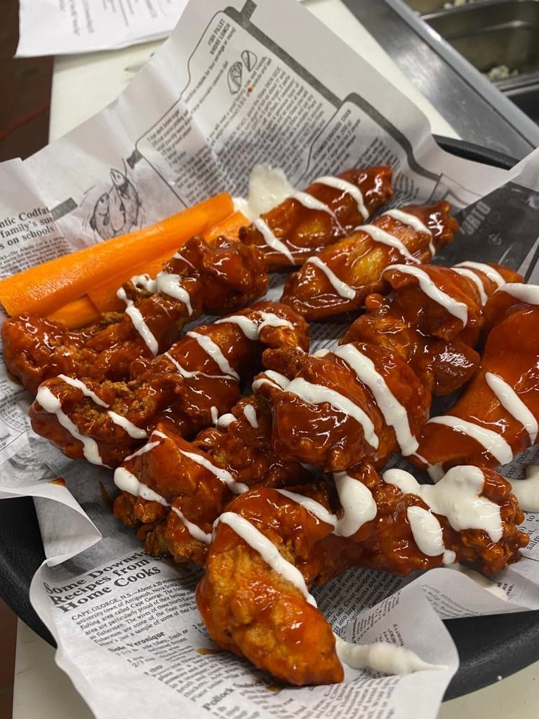 A close up of a plate of chicken wings and carrots on a table.