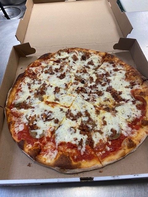 A pizza is sitting in a cardboard box on a table.