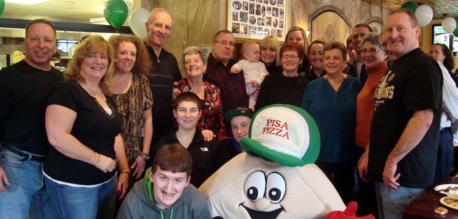 A group of people are posing for a picture with a pizza mascot