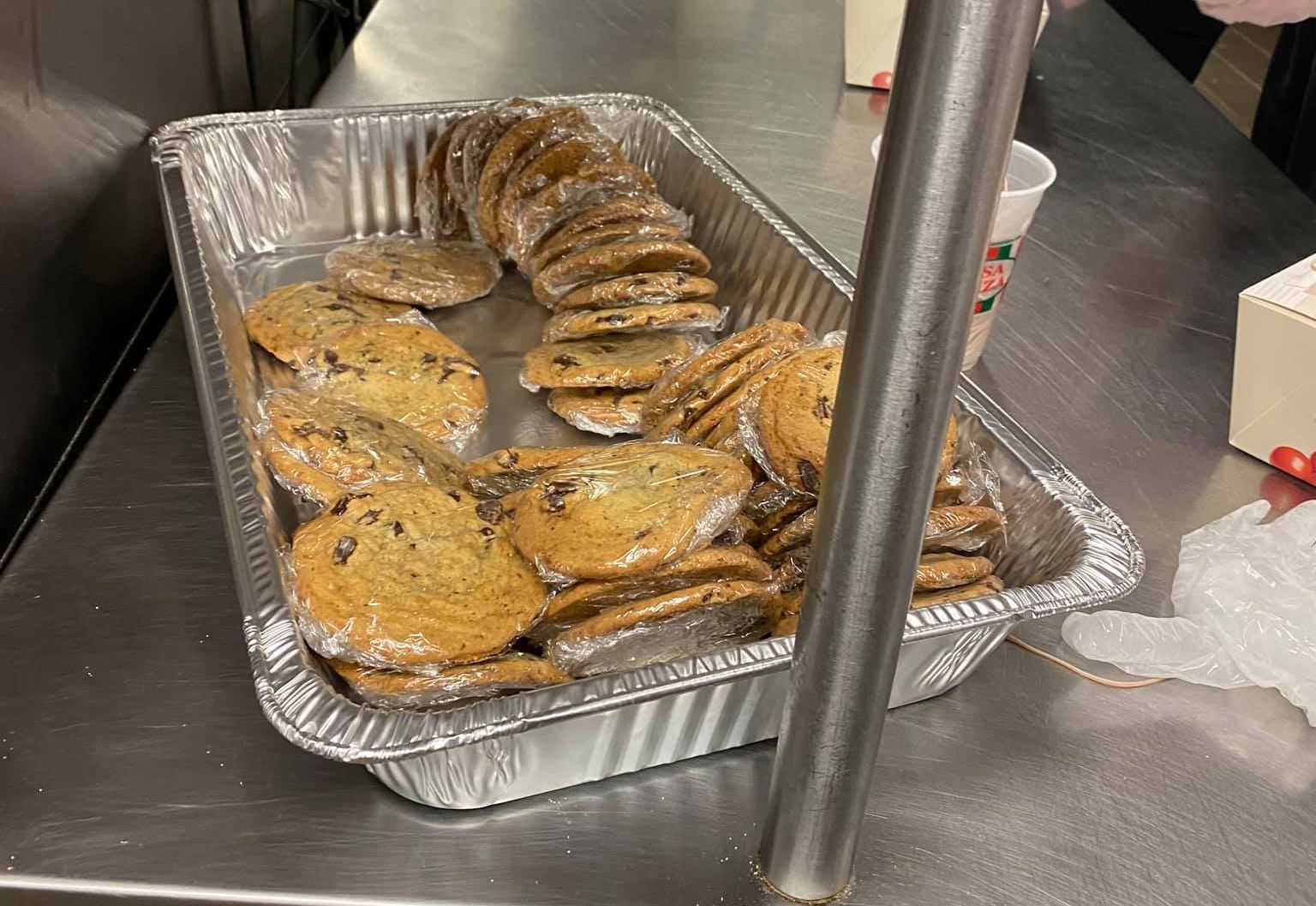A tray of chocolate chip cookies is sitting on a stainless steel counter.