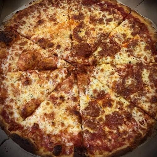 A pizza with pepperoni and cheese is cut into slices and sitting on a table.