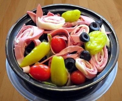A bowl of food with tomatoes peppers olives and ham
