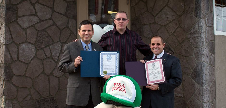 A group of men are posing for a picture and one of them is wearing a green hat that says nba pizza