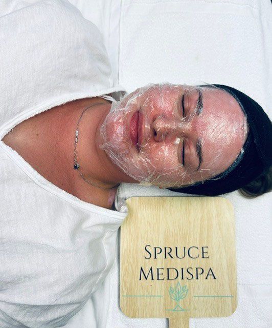 Woman with face wrapped in plastic at Spruce Medispa.