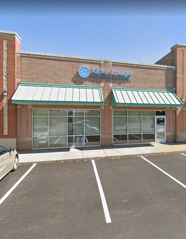 The storefront of an Ideal Image center in a red brick commercial building with green awnings and glass windows.