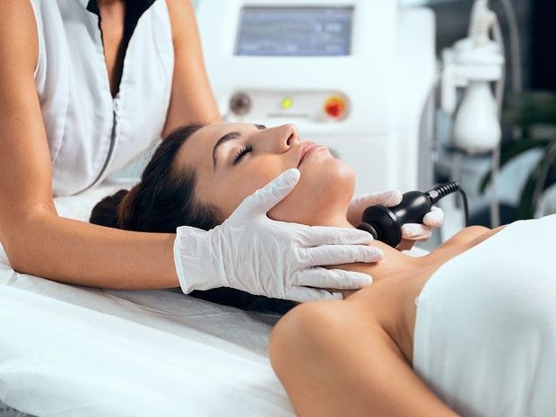 Woman receiving facial treatment with gloved esthetician in a spa treatment room