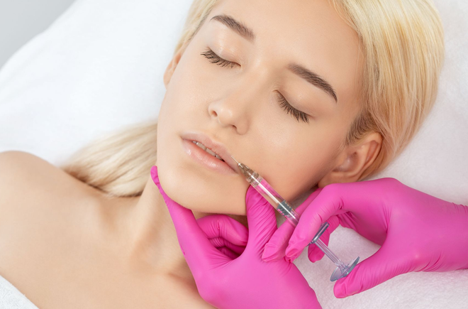 Person receiving an injection in the brow area; gloved hand holding syringe.