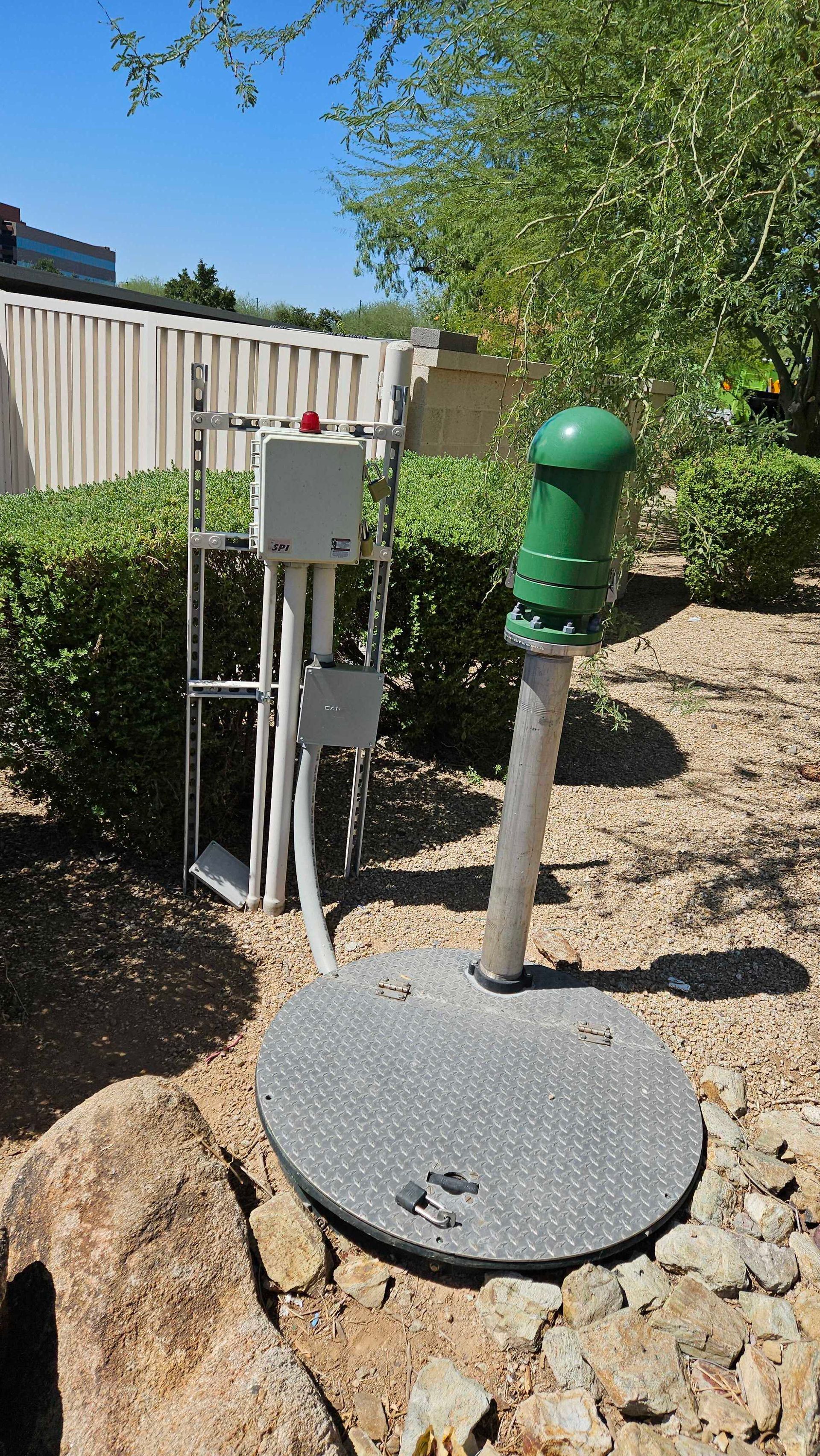 A green water pump is sitting on top of a manhole cover.
