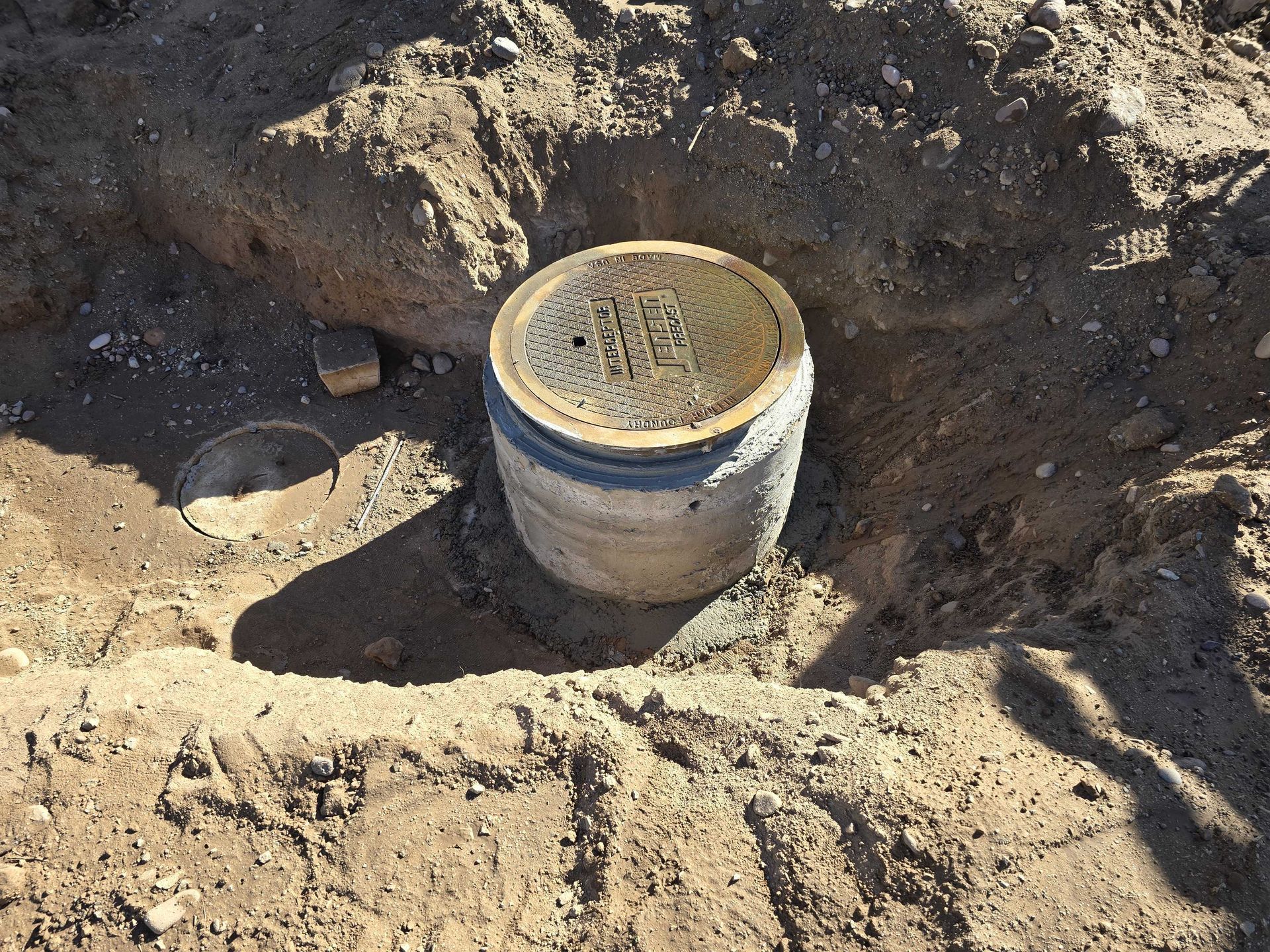A concrete pipe is sitting in the dirt with a lid on it.