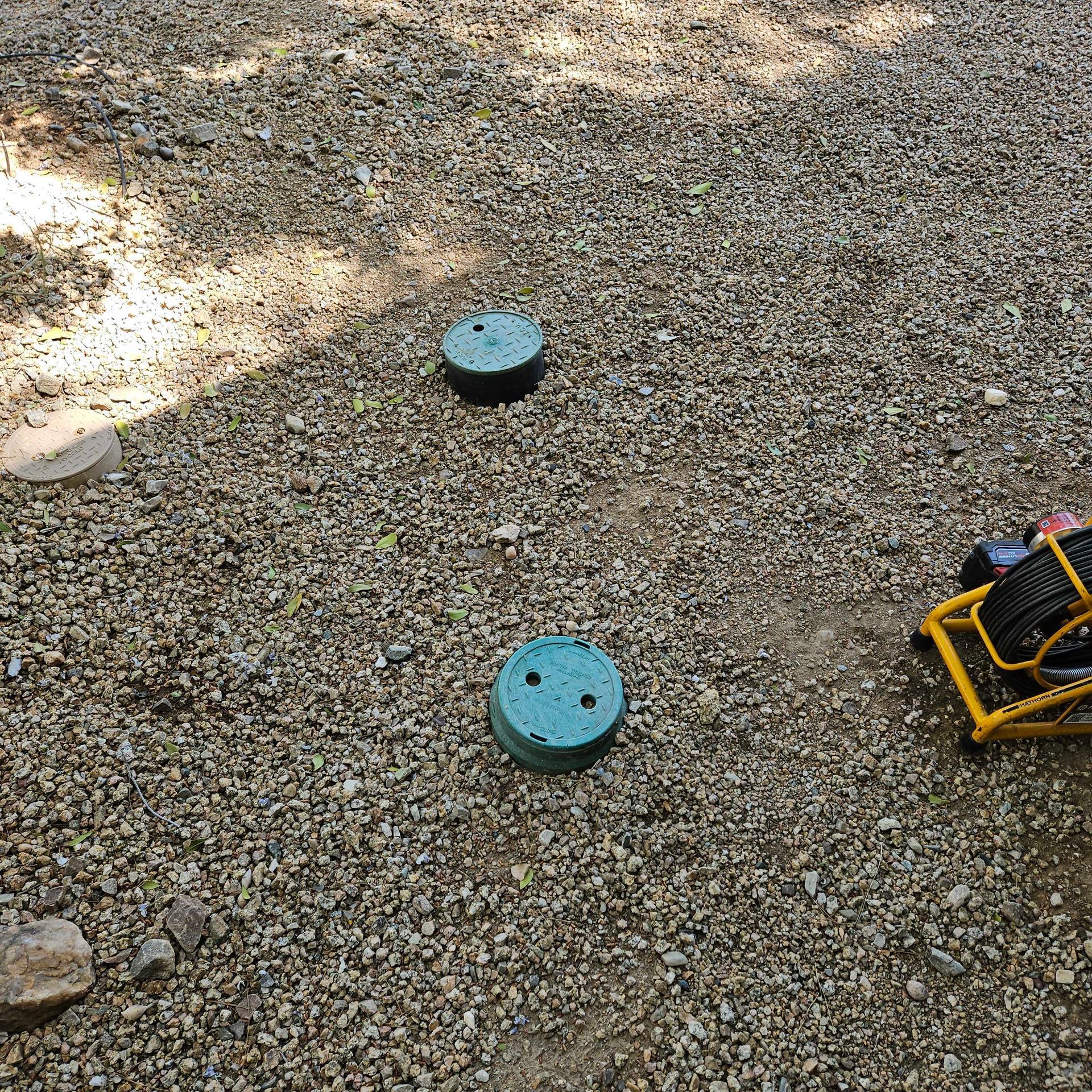 A camera is sitting on the ground next to a pile of gravel.