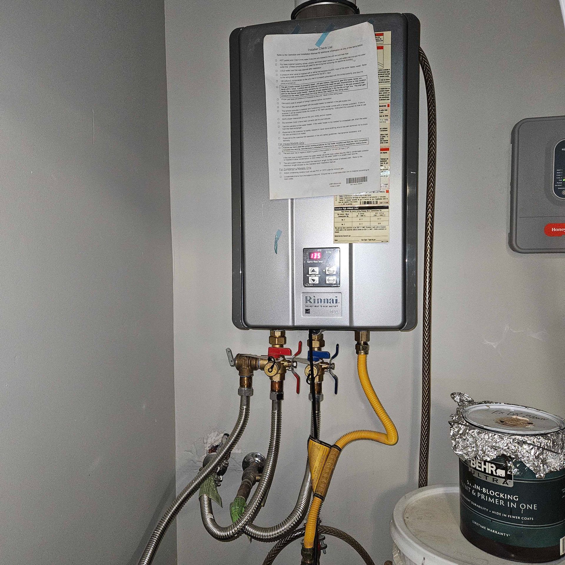 A water heater is connected to a bucket of paint