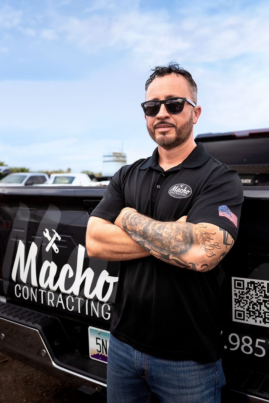 A man is standing in front of a truck with his arms crossed.