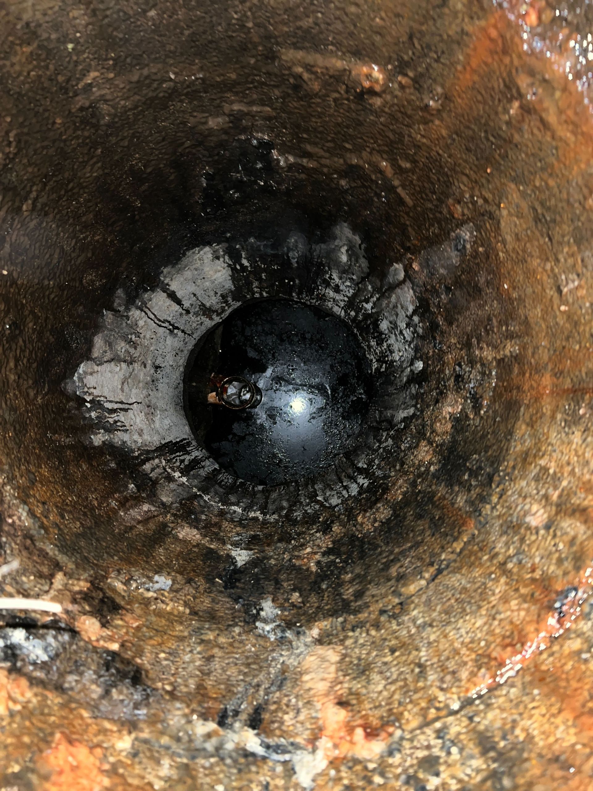 A close up of a hole in the ground with a ball in it.