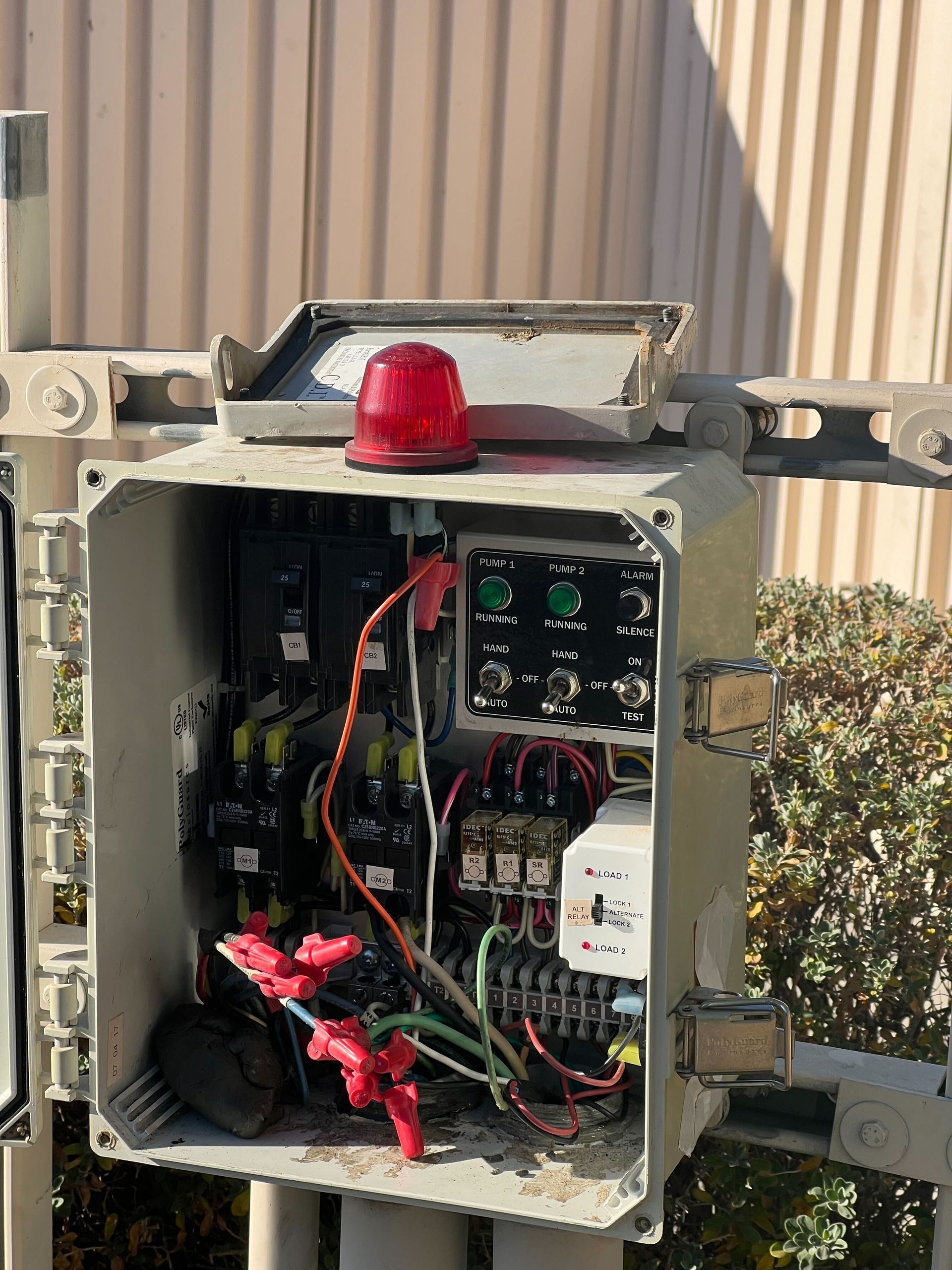 A broken electrical box with a red light on top of it.