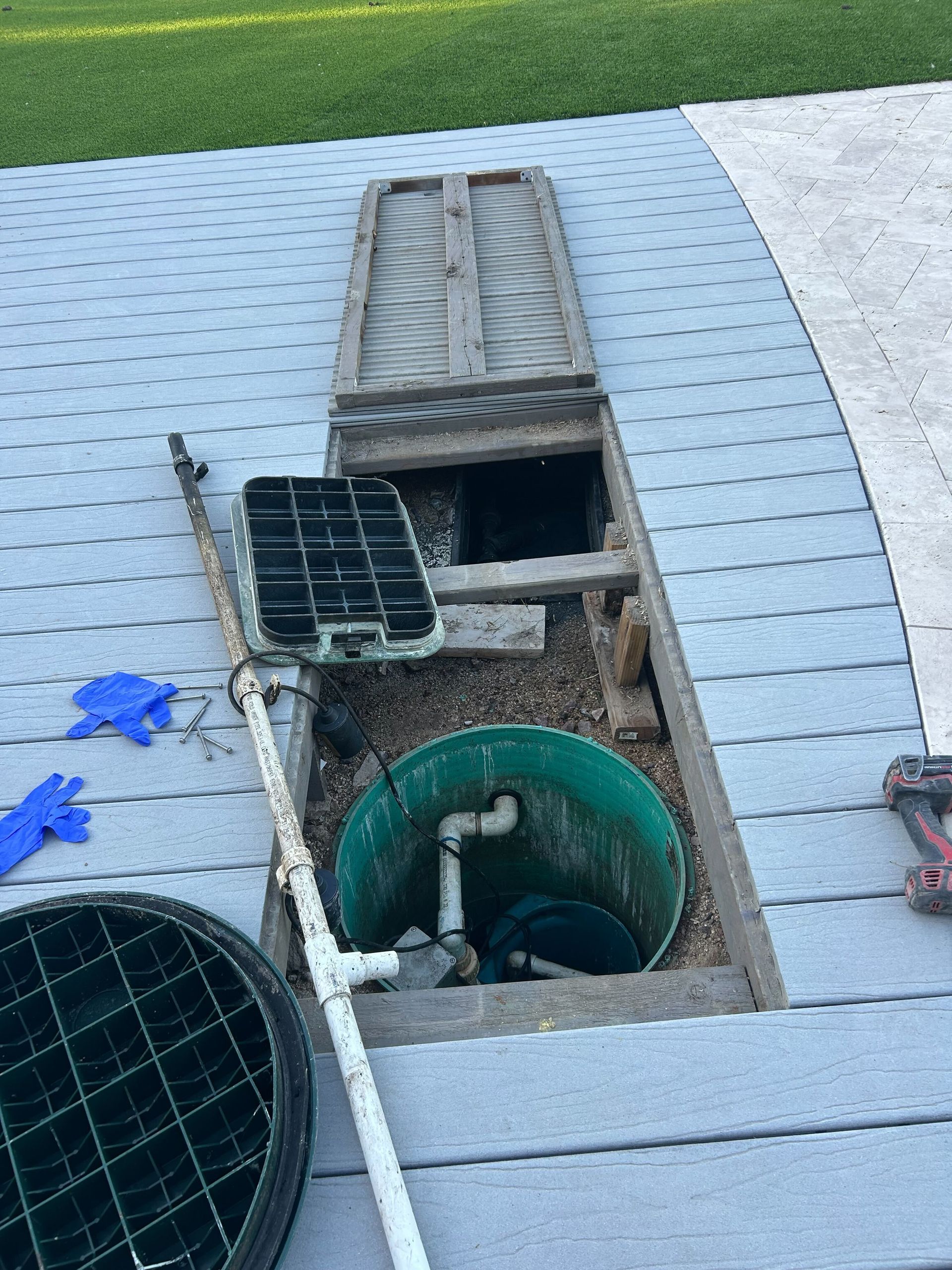 A hole in the ground with a green bucket in it.