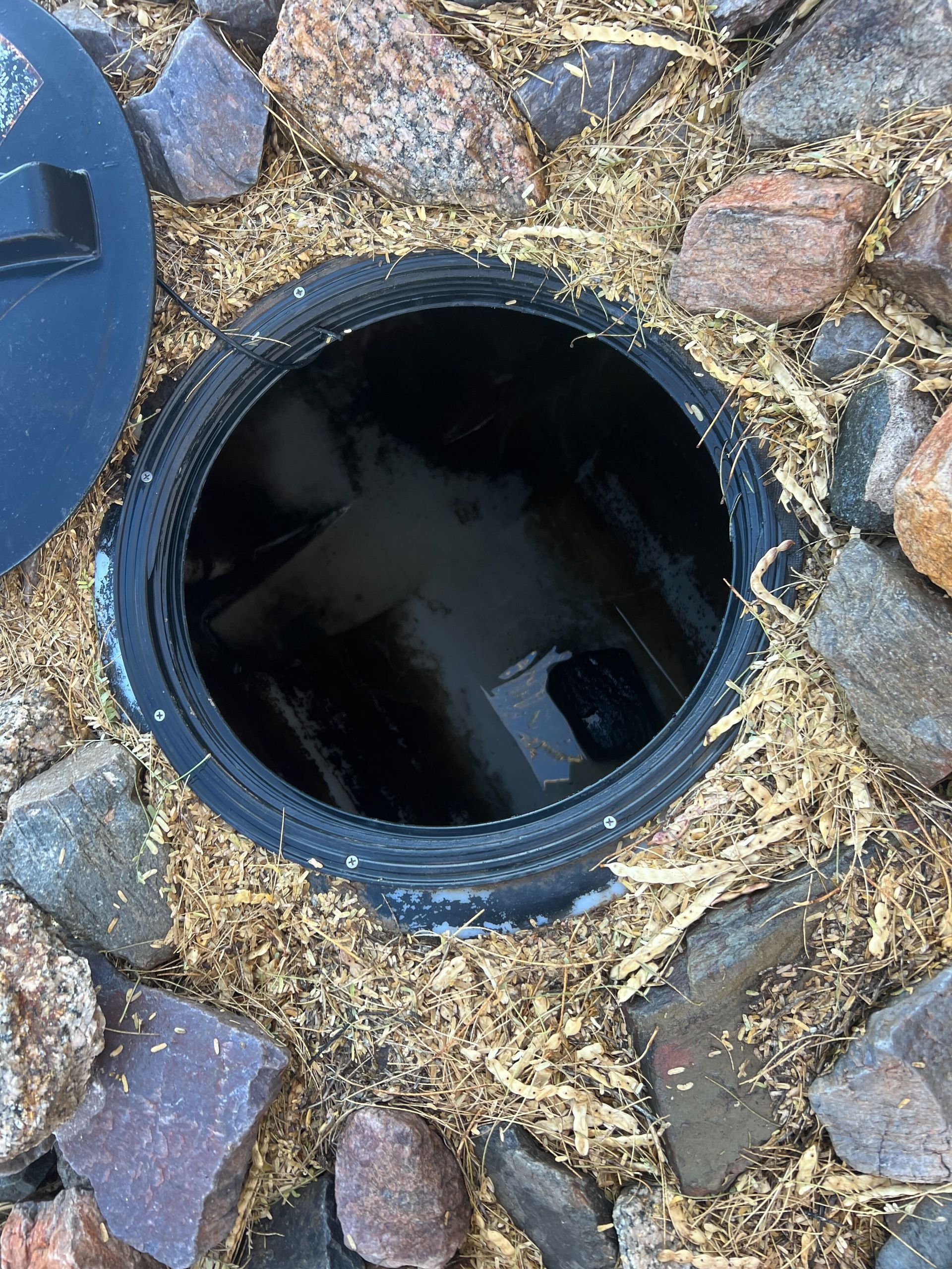 A manhole cover is sitting on top of a pile of rocks.