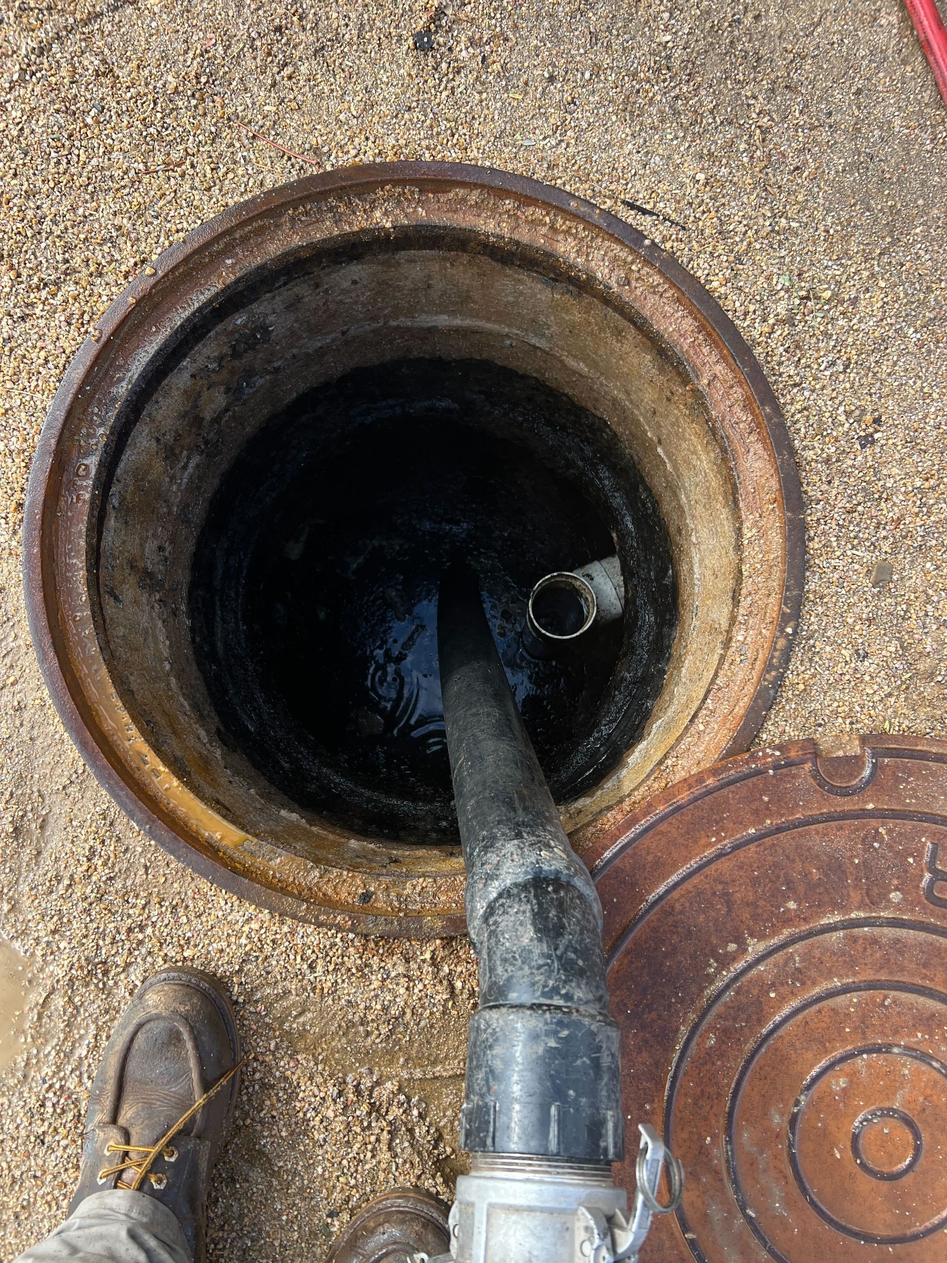 A manhole cover with a hose coming out of it.