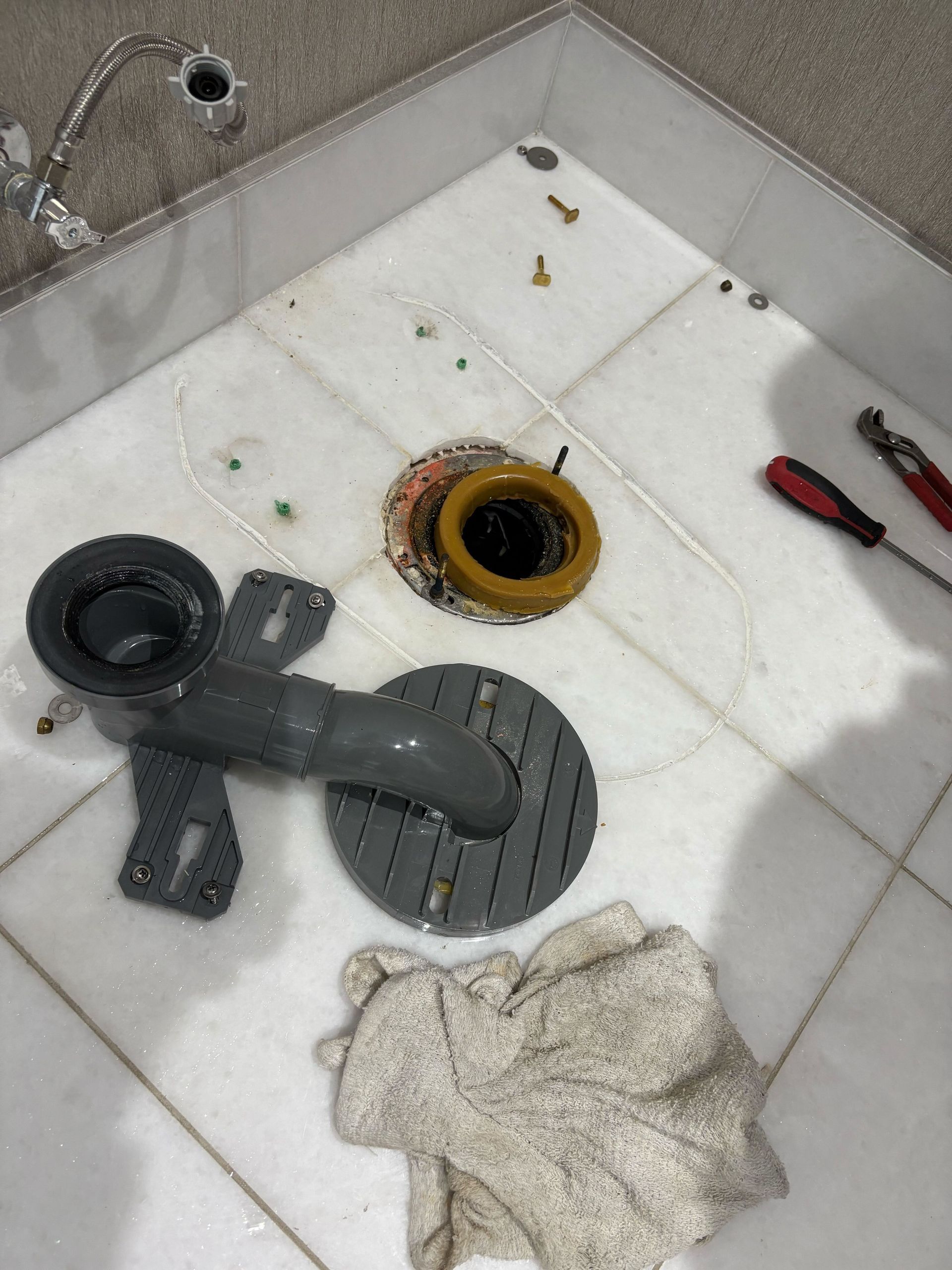A toilet is being repaired in a bathroom with tools on the floor