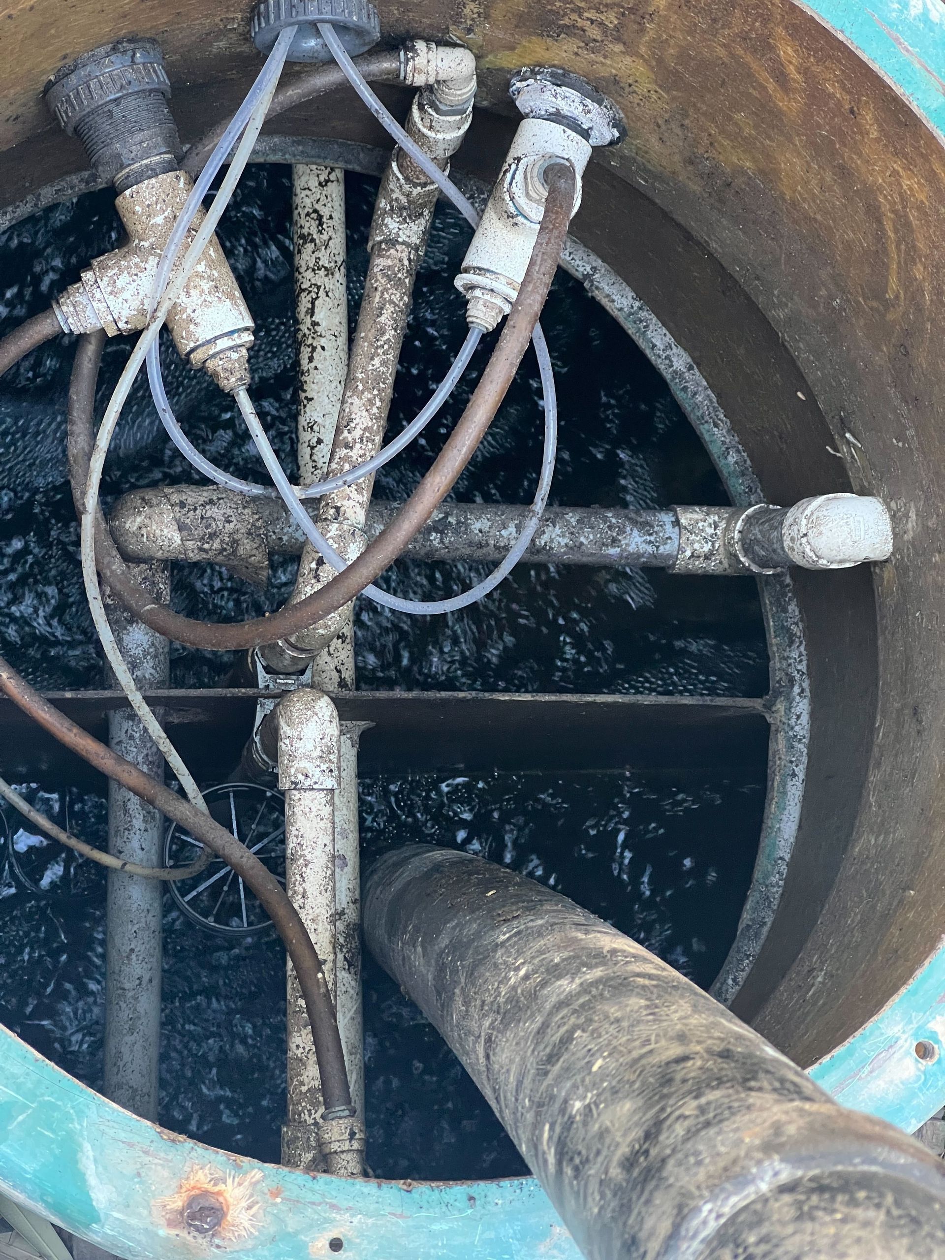 A close up of a drain with pipes and wires coming out of it