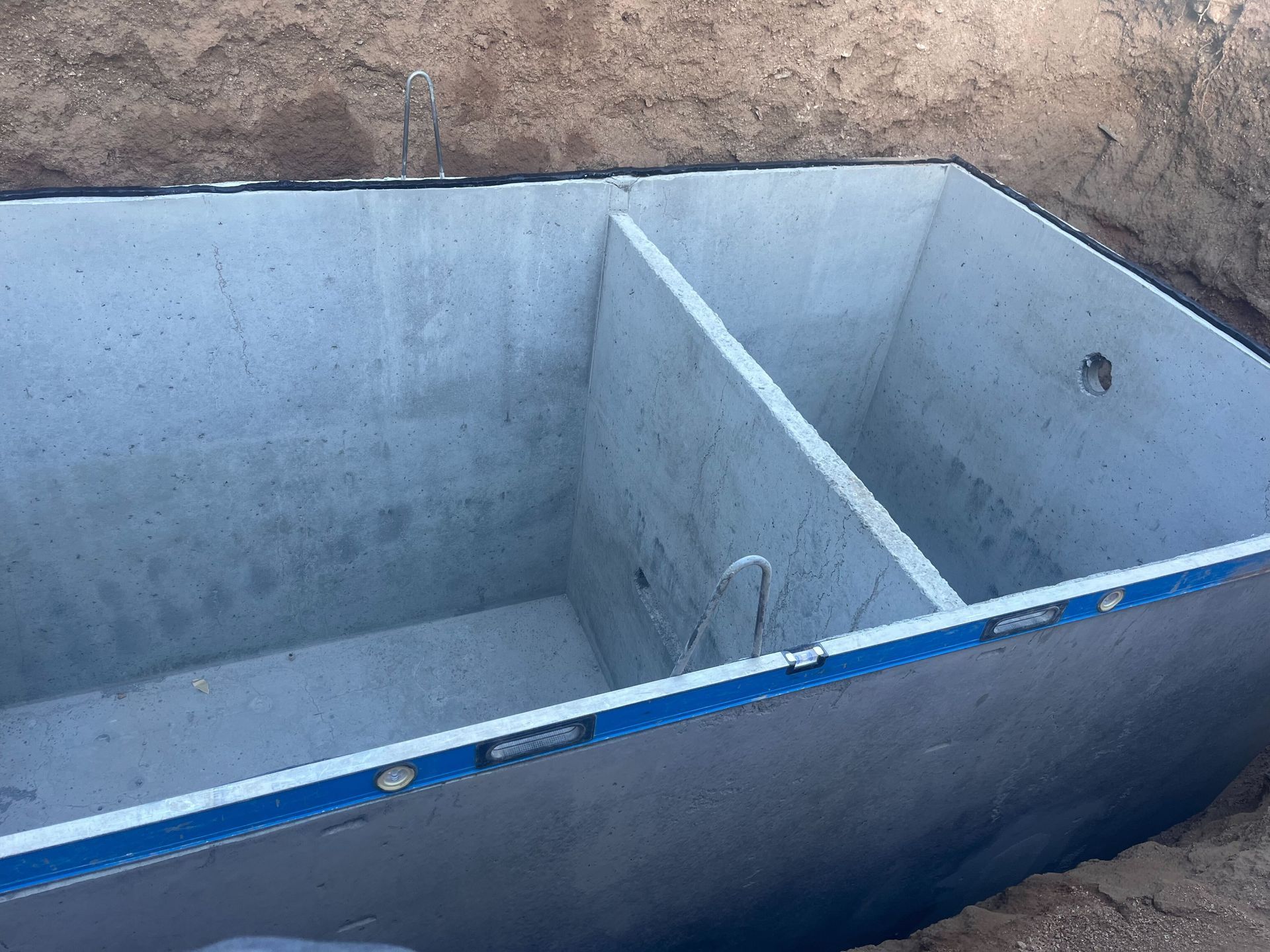 A large concrete tank is being built in the dirt.