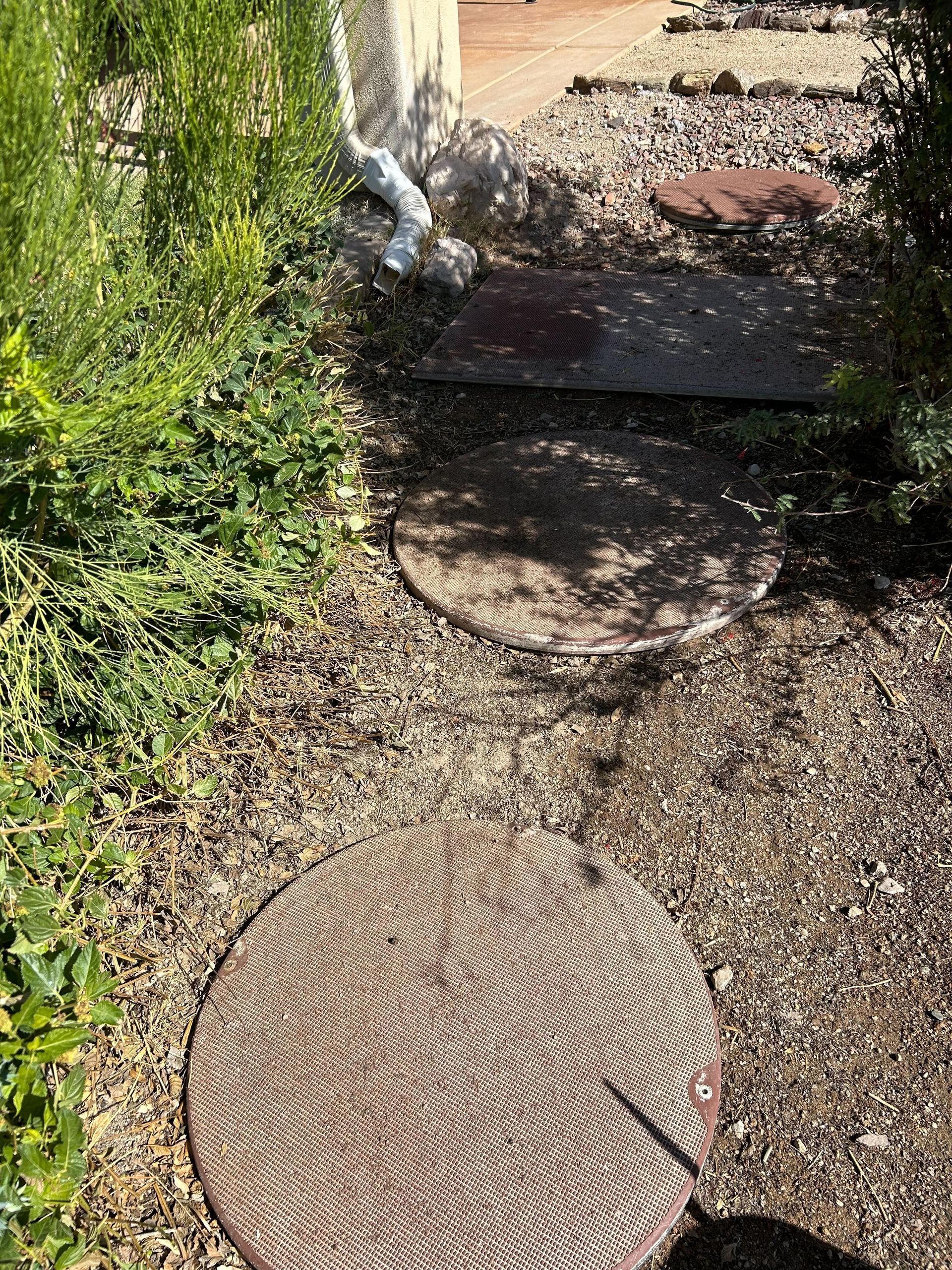 A manhole cover is sitting on the ground next to a gravel path.