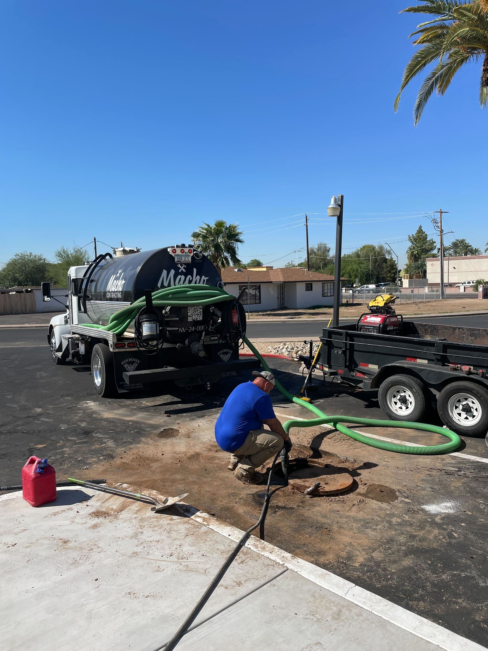 A man is kneeling in front of a septic truck.