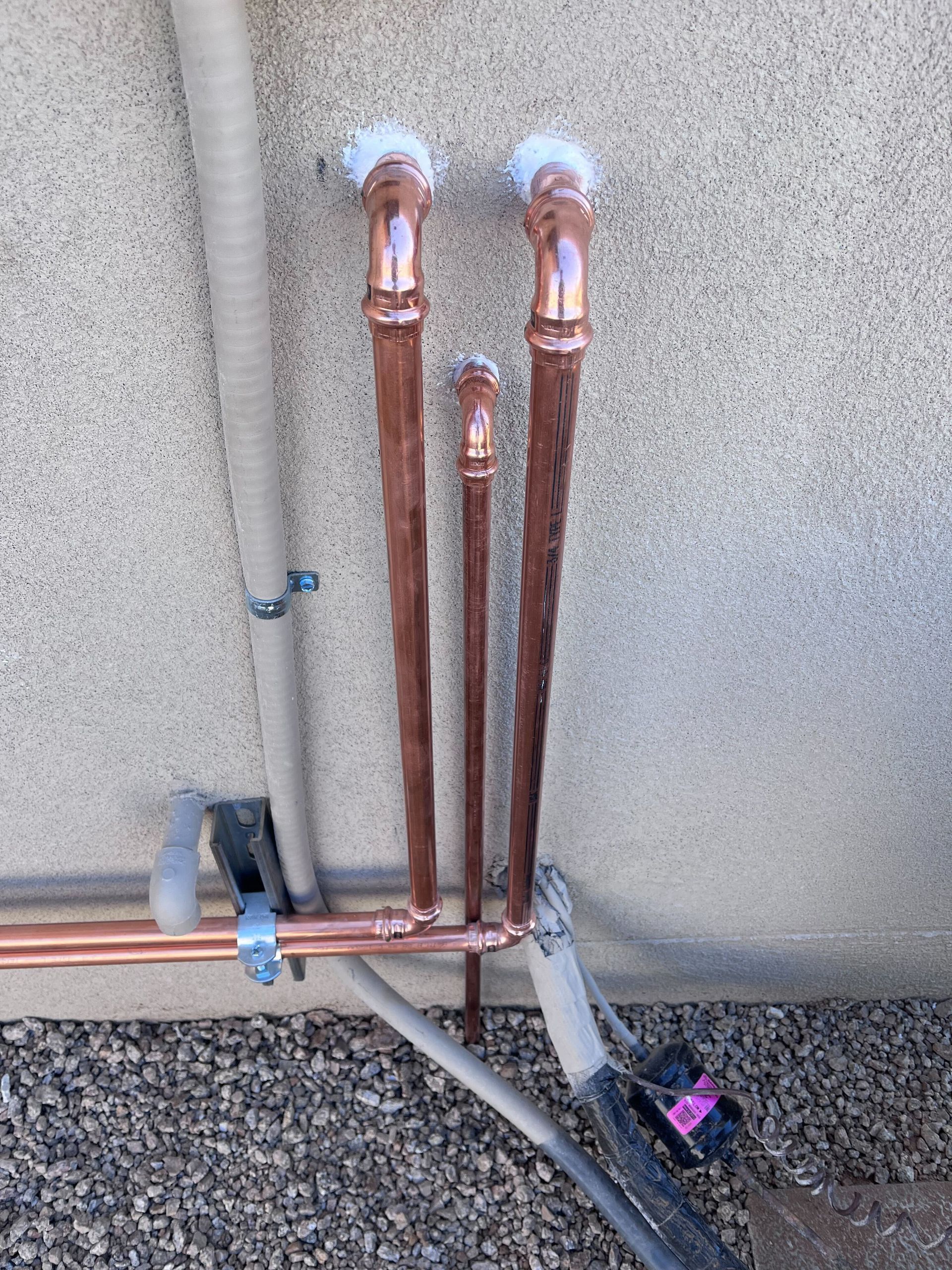 Copper pipes are being installed on the side of a building.