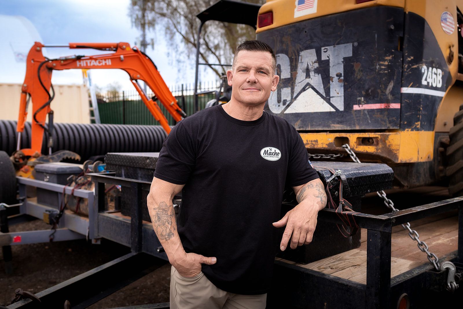 A man is standing in front of a cat excavator.
