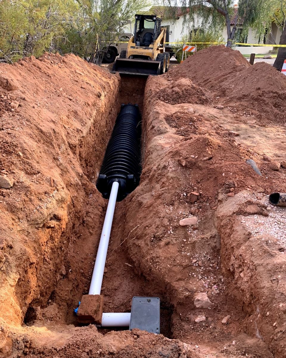 A pipe is being installed in a trench in the dirt.