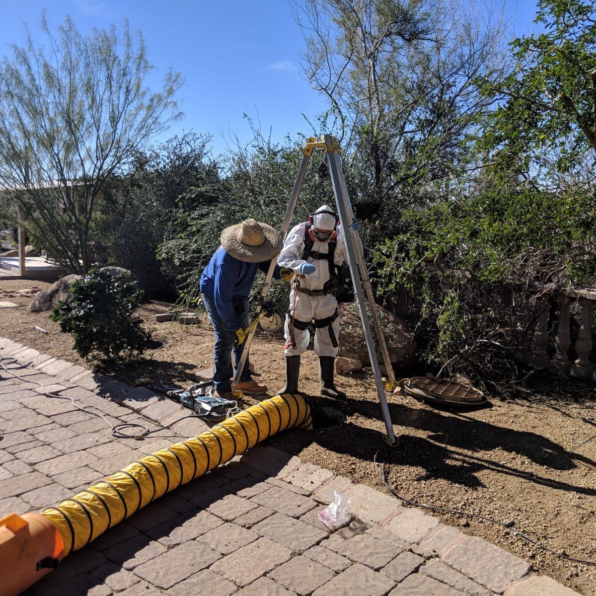 Two men are standing next to a yellow hose on a sidewalk.